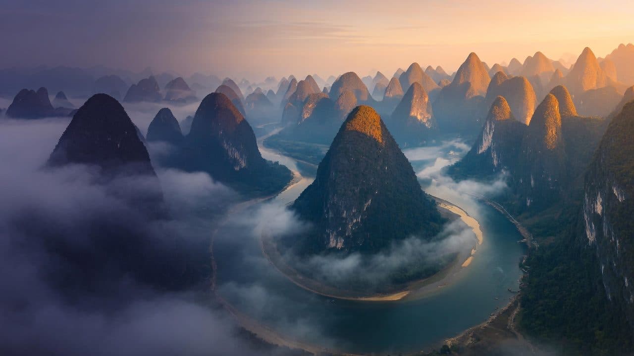 Karst peaks and a river bend under sunrise mist