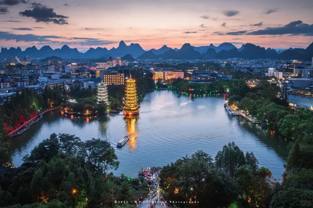The Sun and Moon pagodas lit above the Four Lakes in Guilin at dusk