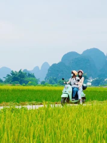 Riders on an electric scooter on a track through the Yangshuo rice fields