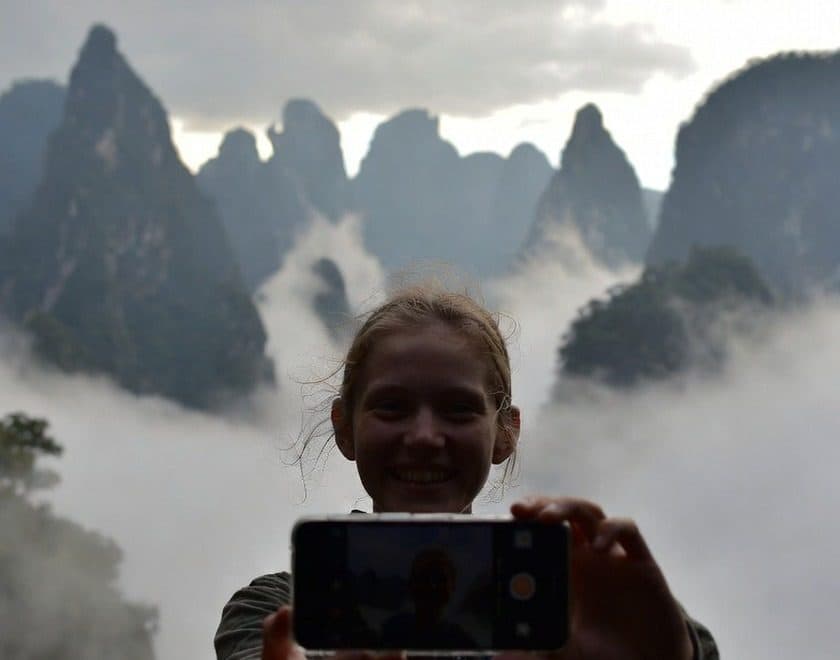 A traveller photographing karst peaks above a sea of cloud