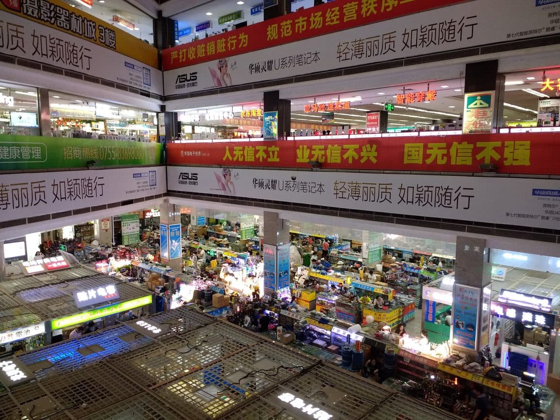 Looking down through the atrium of a Huaqiangbei electronics market, several floors of stalls under signage