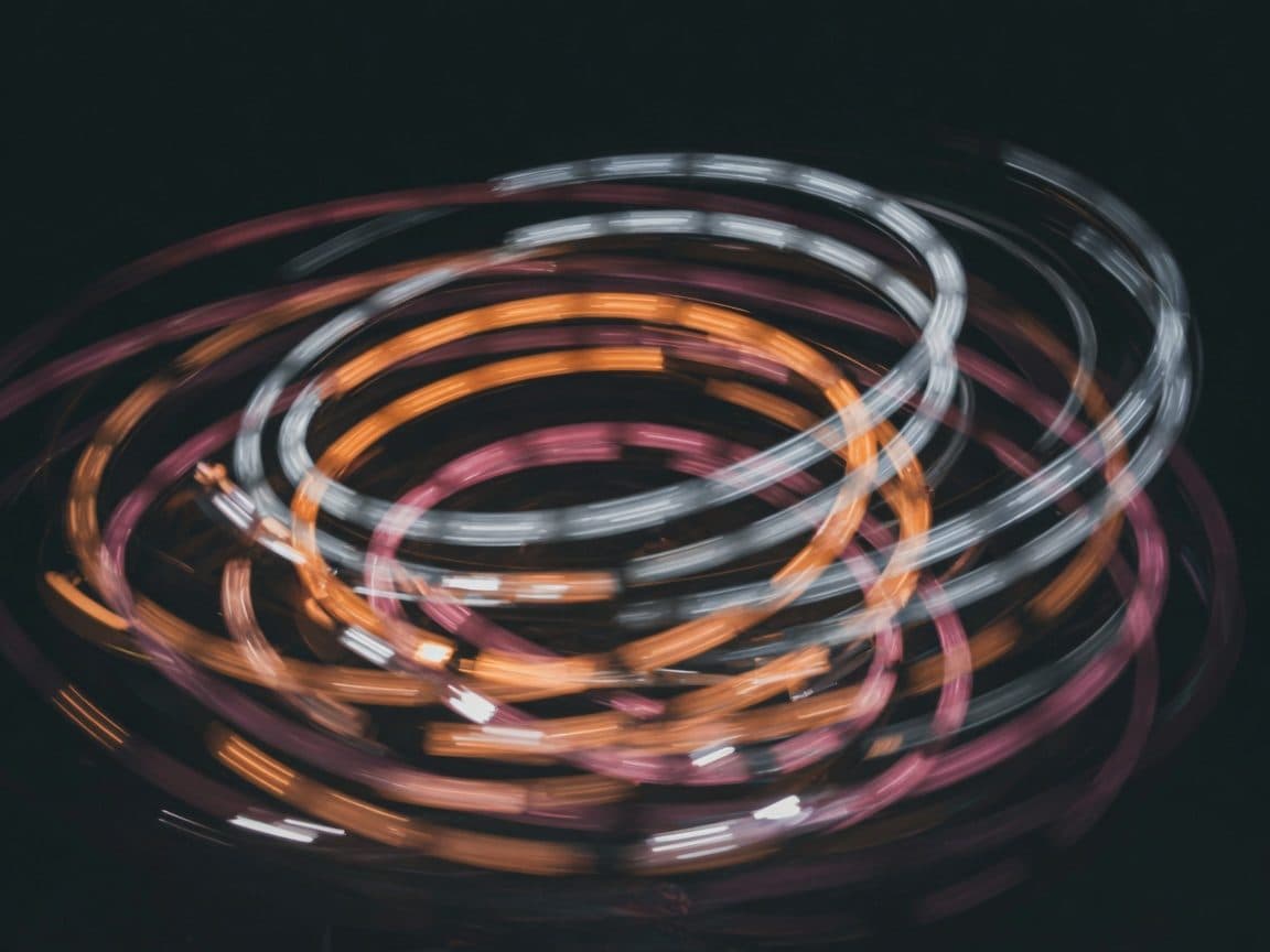 Long-exposure light trails from a spinning fairground ride against a black sky