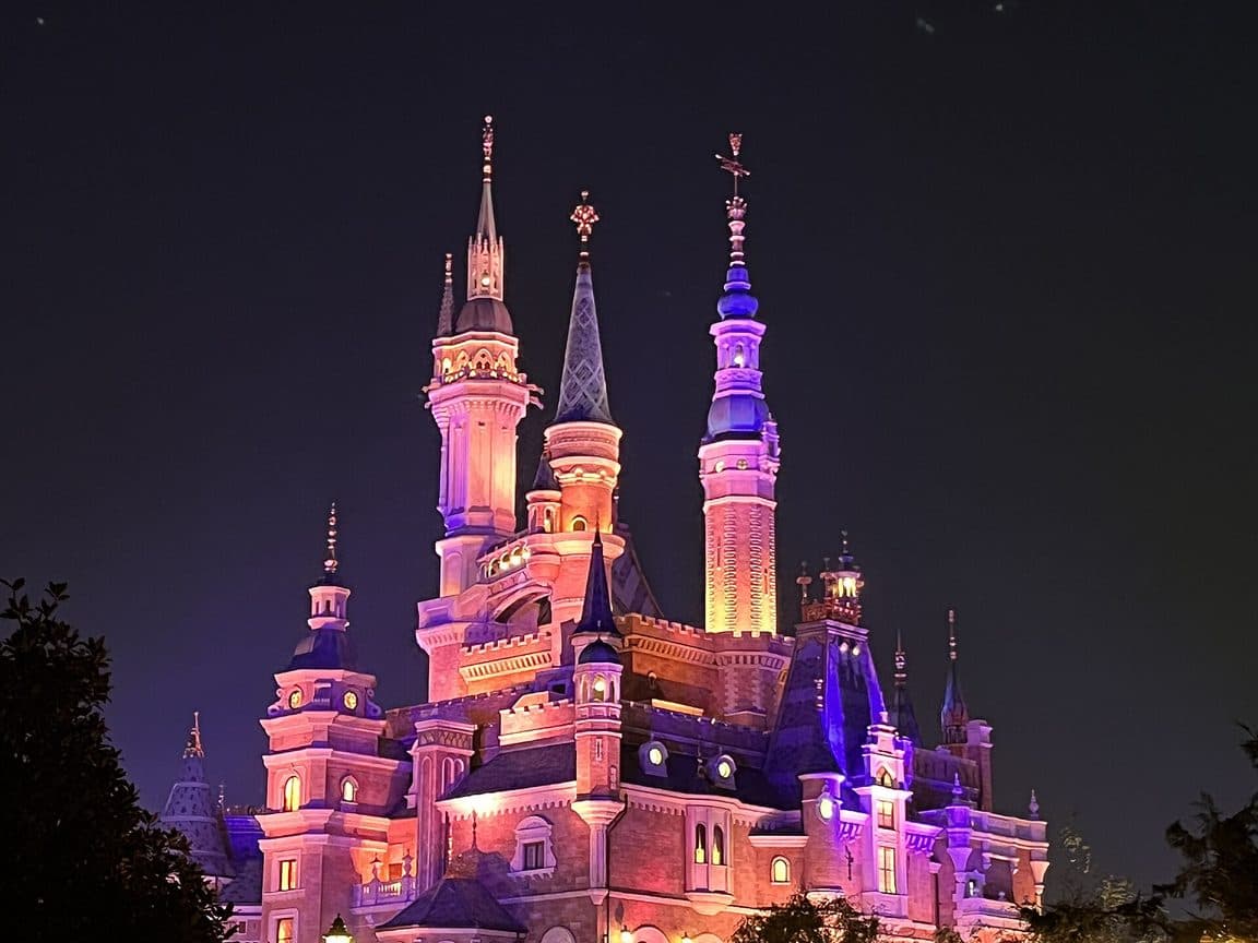 The Enchanted Storybook Castle lit at night above the crowds at Shanghai Disneyland