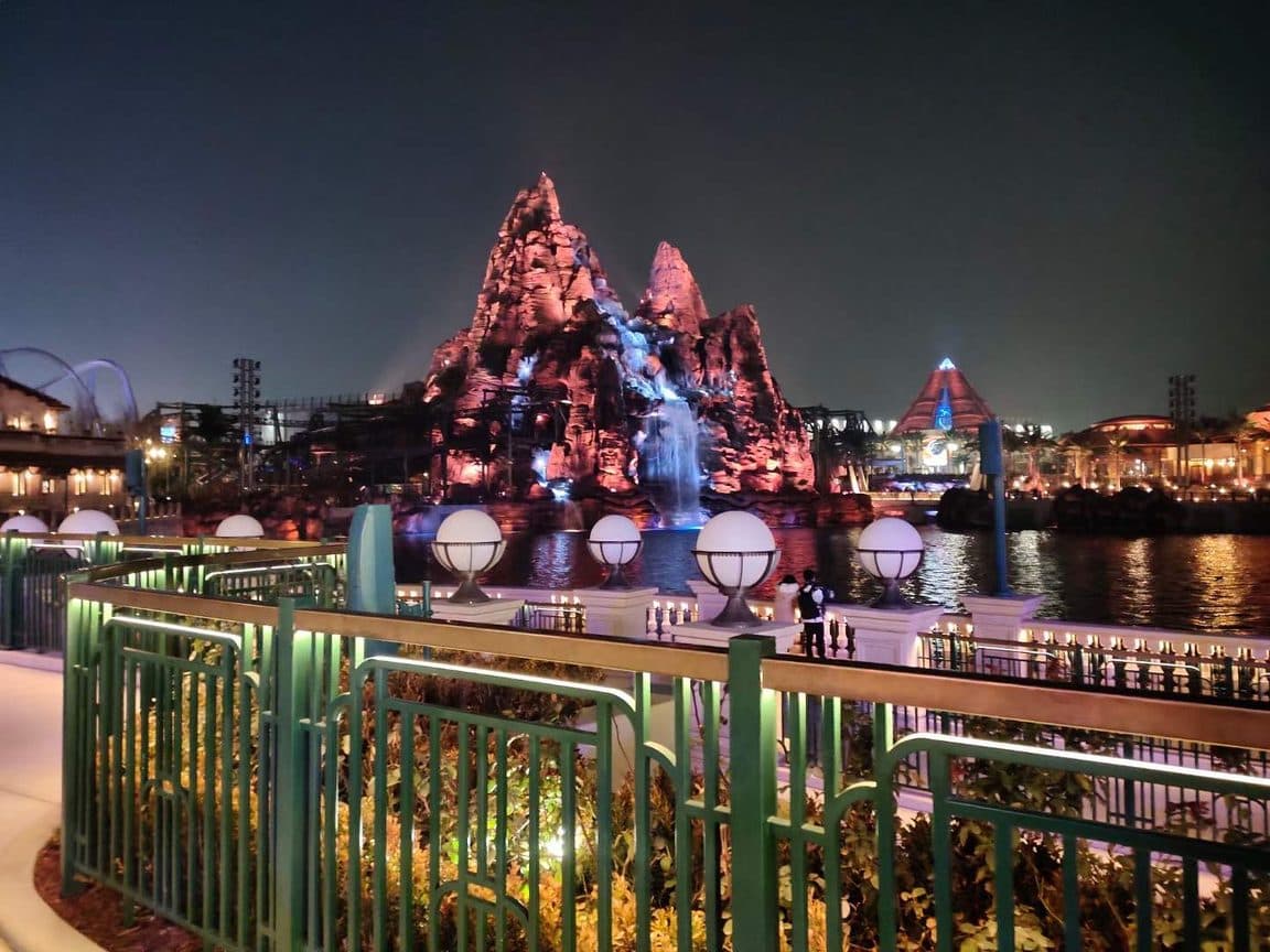 Universal Beijing Resort seen across the water at dusk, themed rockwork lit from below