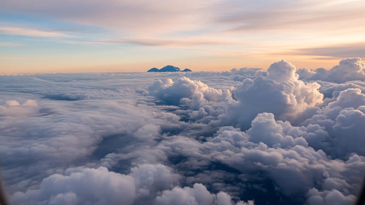 Cloud layer seen from cruising altitude with distant ranges on the horizon