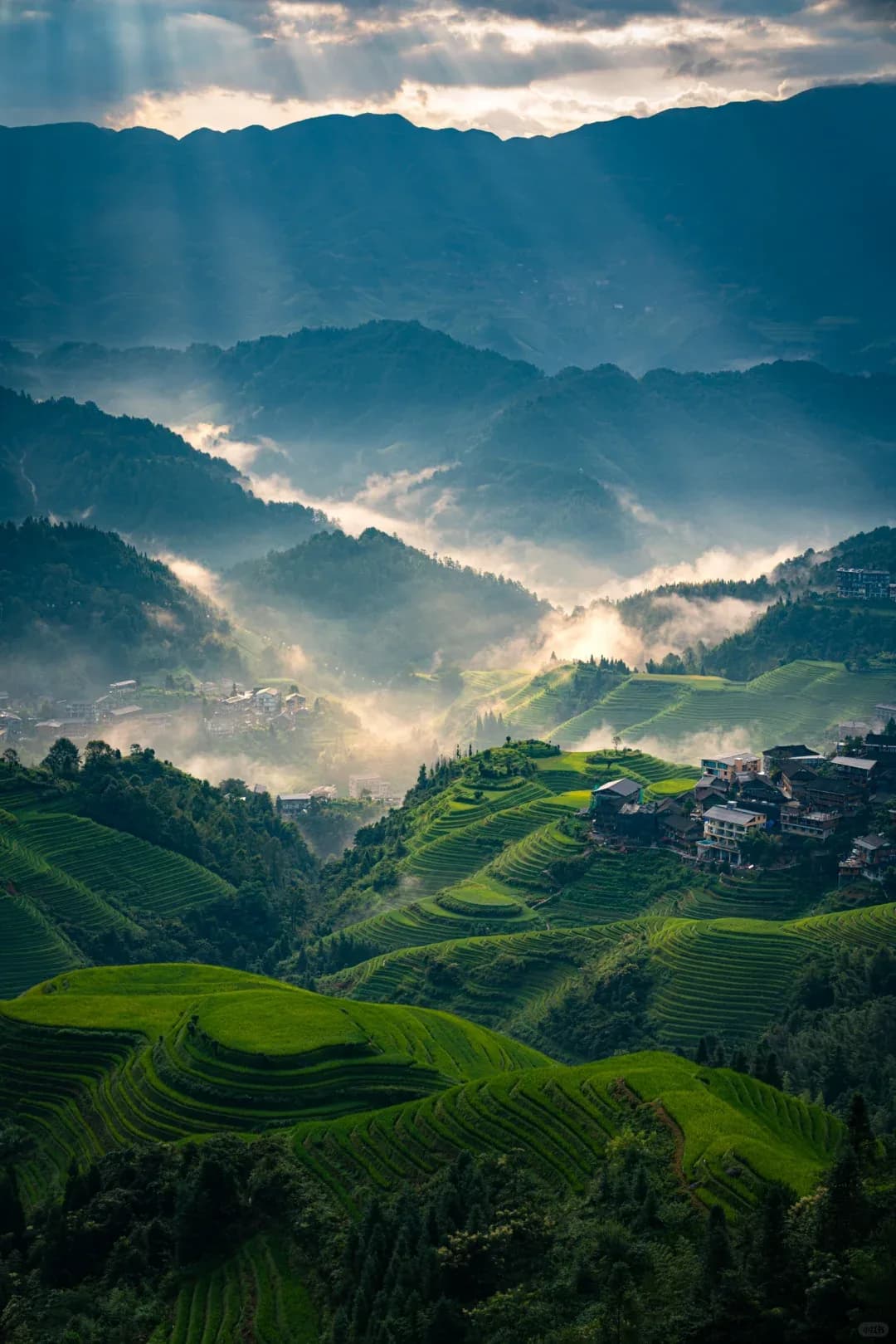 Sun breaking through mist over the Longji terraces and the village below