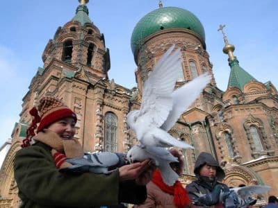 Feeding doves in the square outside the Church of St Sophia, Harbin