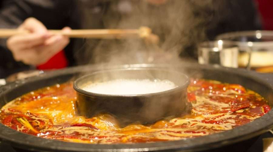 Sichuan hotpot simmering at the table